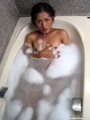 Ladyboy lying in bath bubble bath arm covering breasts